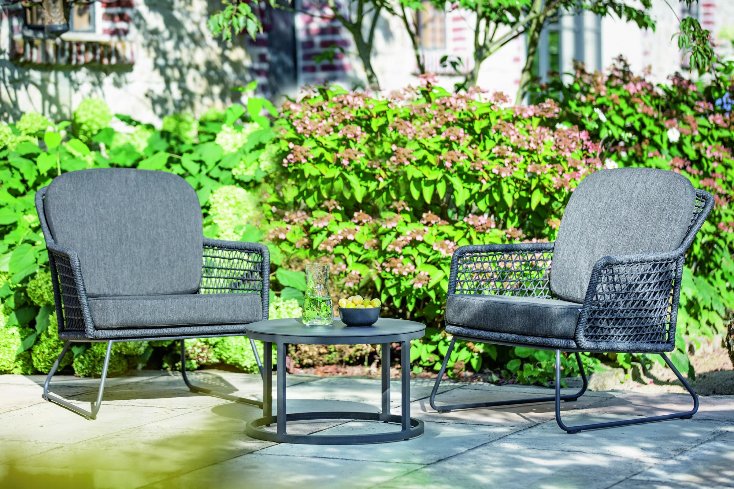 Zwei gepolsterte Outdoor-Sessel in einer Gartenanlage